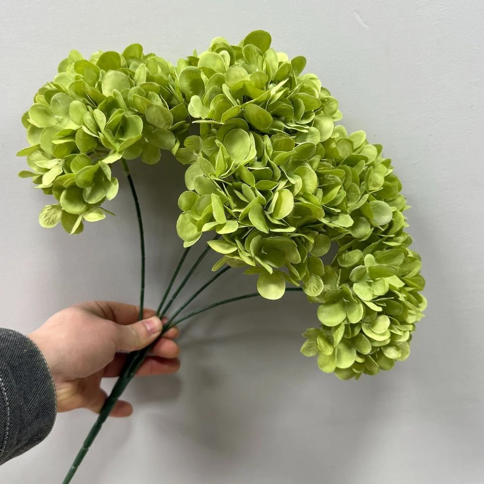 Green artificial hydrangea bush held by its stems