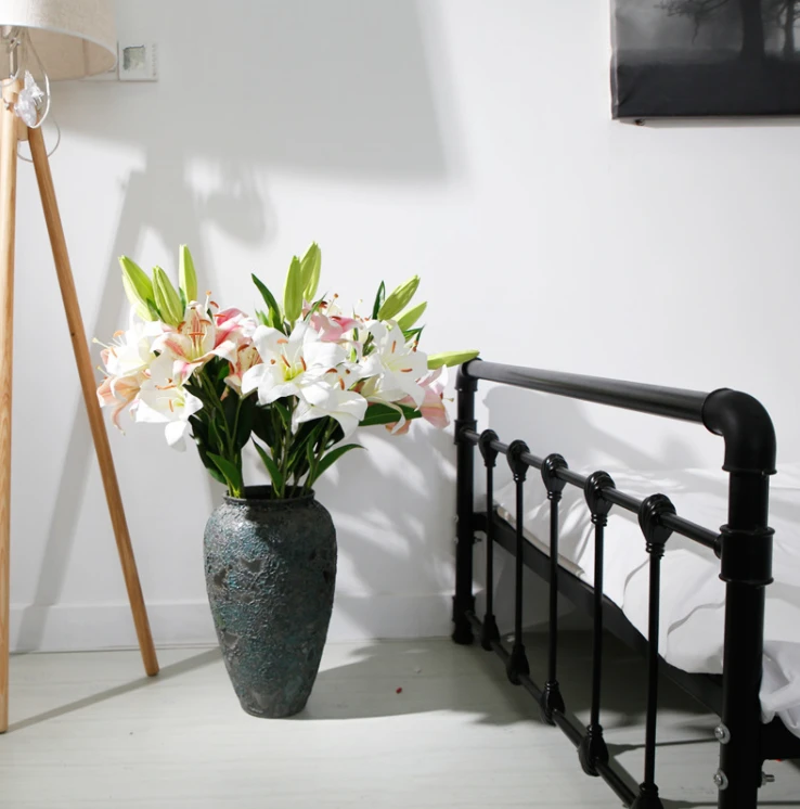 Pale pink and white artificial lilies with green buds arranged in a vase
