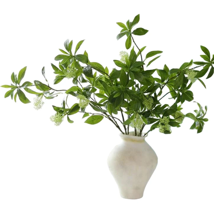 Branching artificial green foliage arranged in a white sculptural vase