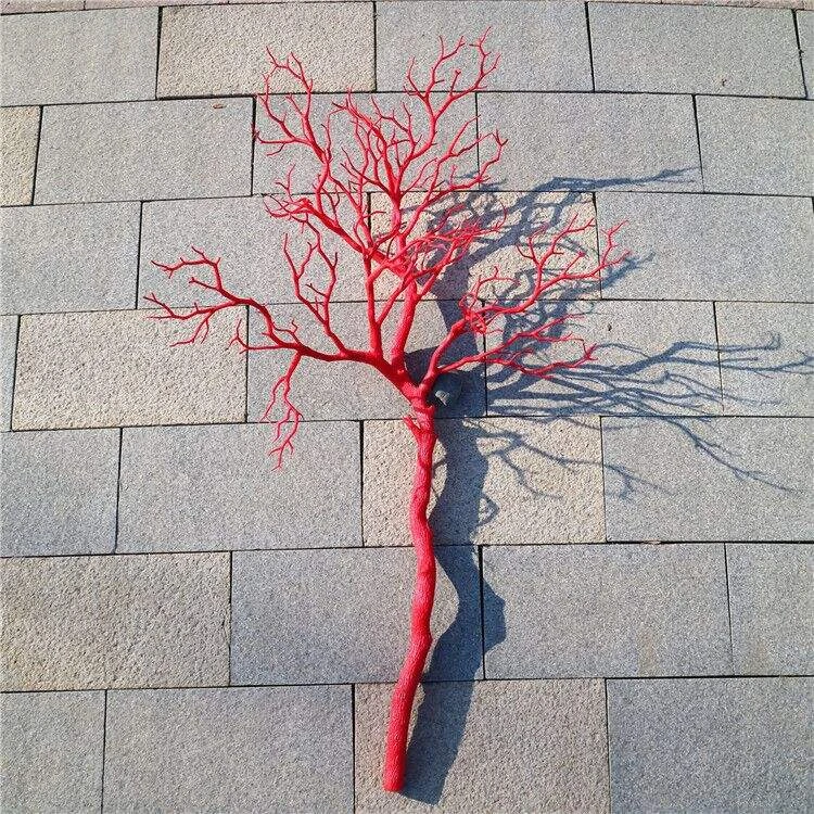 Red coral-style artificial decorative branch against a grey wall