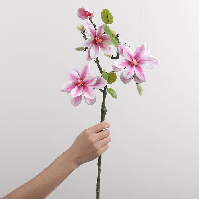 Pink artificial open flowers and buds along a brown branch held upright