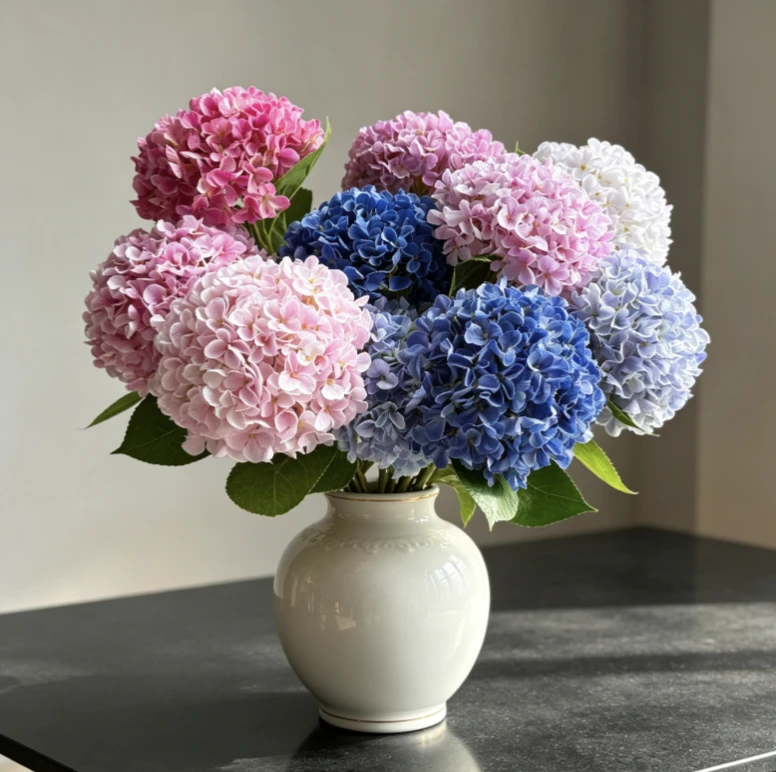 Pink, burgundy and blue artificial hydrangeas arranged in a pale vase