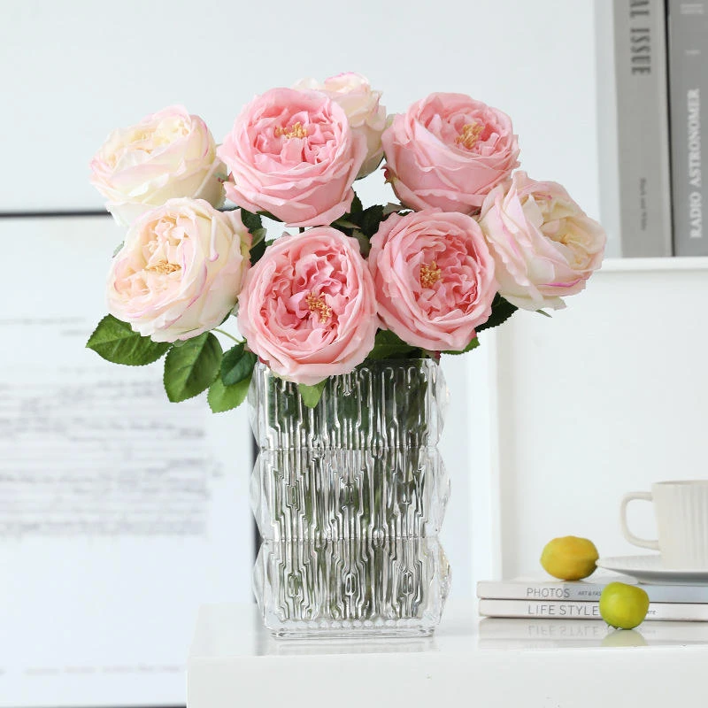 Pink and cream artificial roses arranged in a clear ribbed glass vase